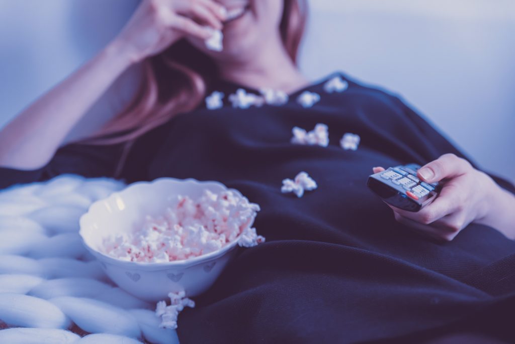 Woman watching TV eating popcorn