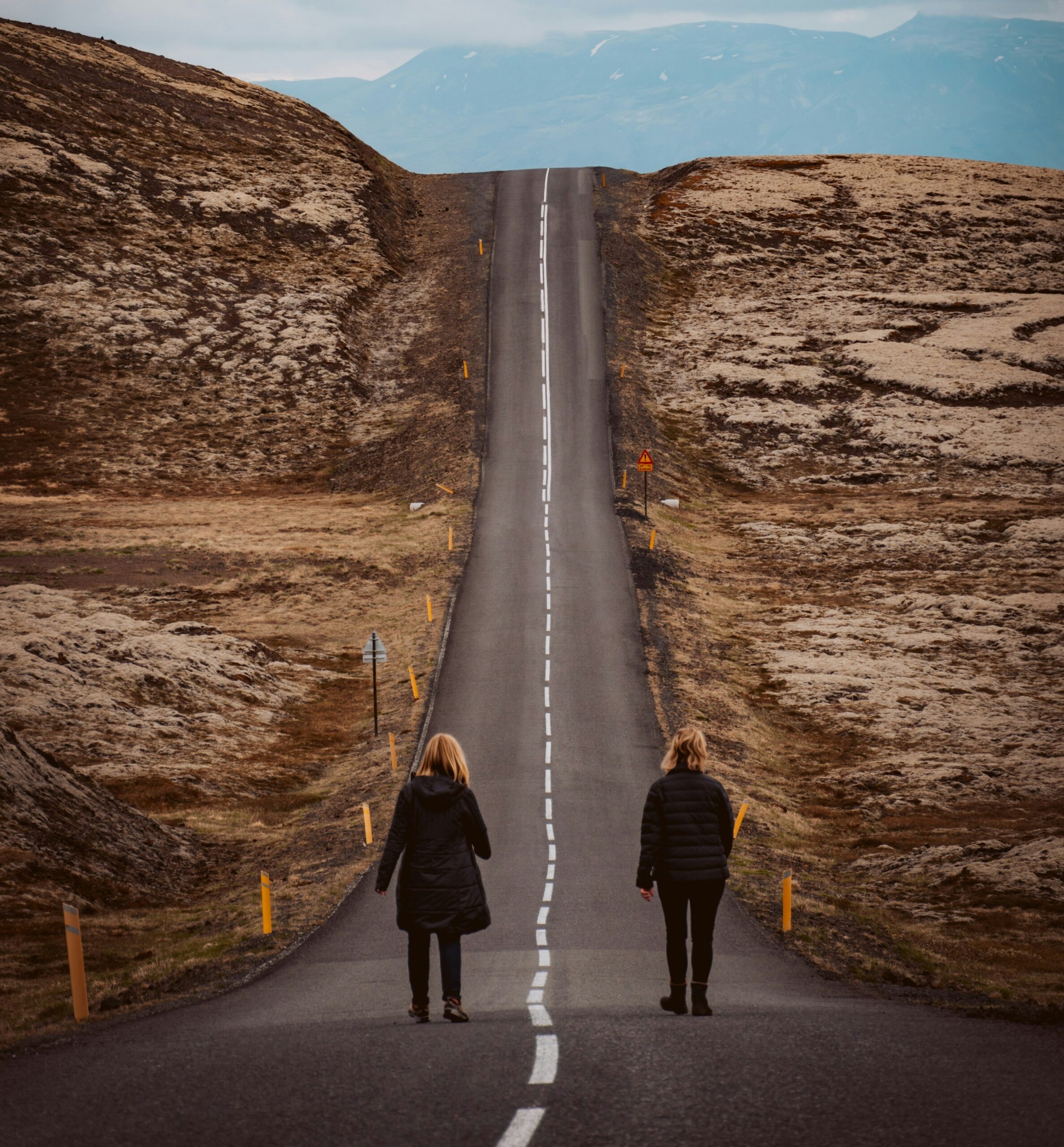 Two people walking together down a remote road in iceland