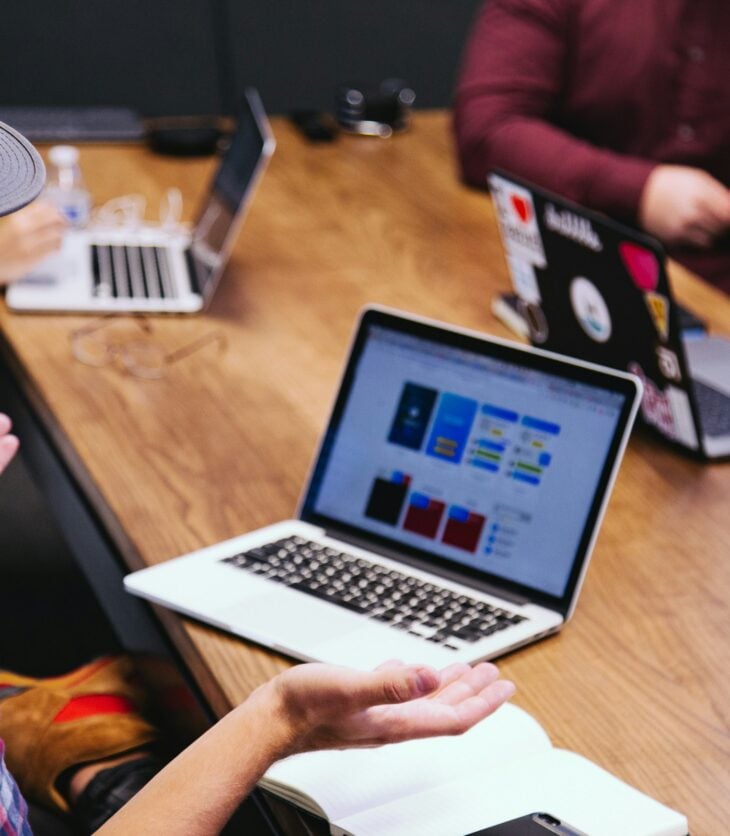 A man sitting at a desk using a laptop while explaining soemthing.